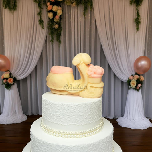 Edible scooter cake topper with pink flowers, displayed on a white wedding cake with elegant draped backdrop – Makai Cake Decorating Supplies