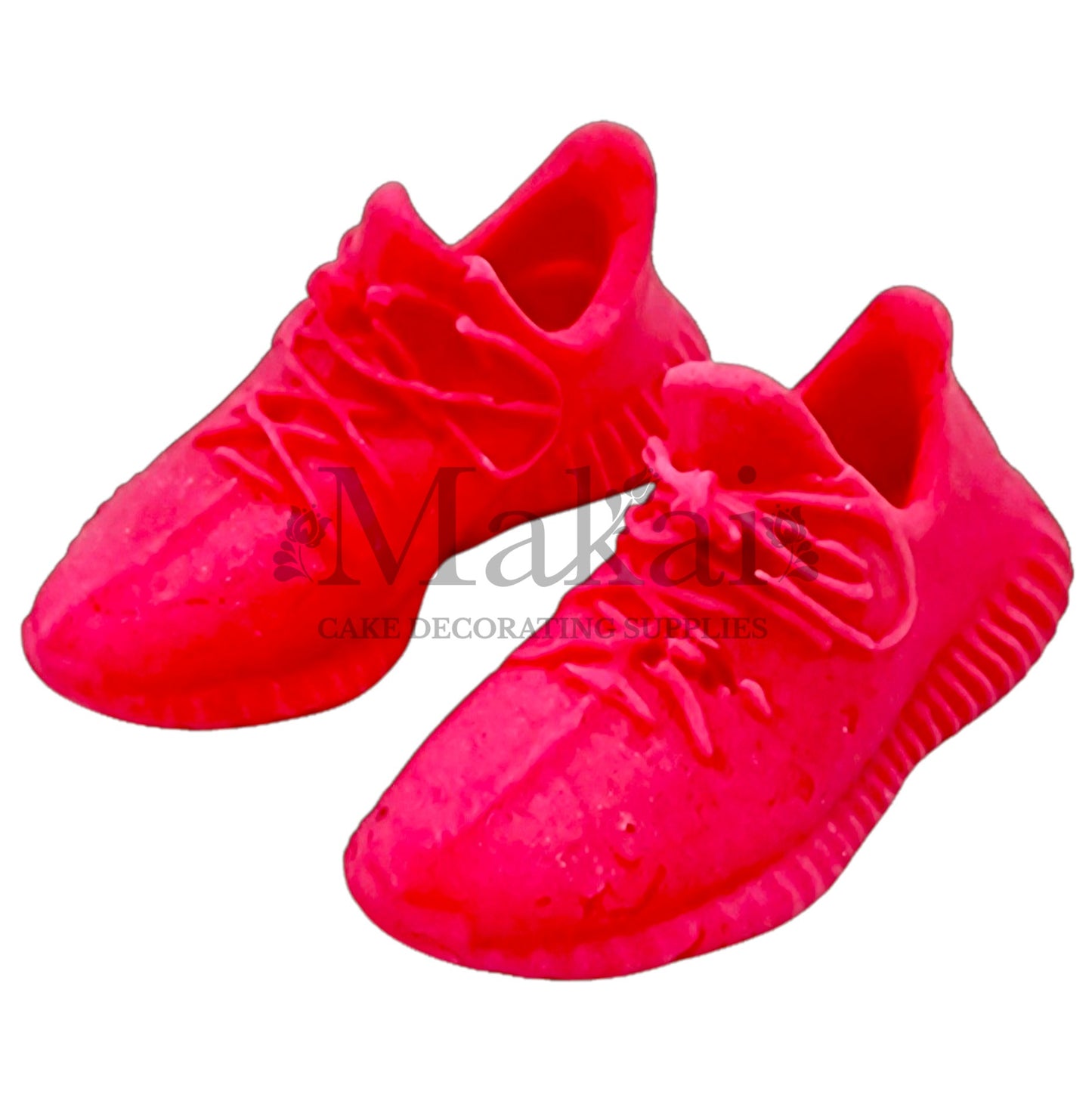 Pair of bright‑pink fondant running‑shoe toppers for sporty birthday cakes.