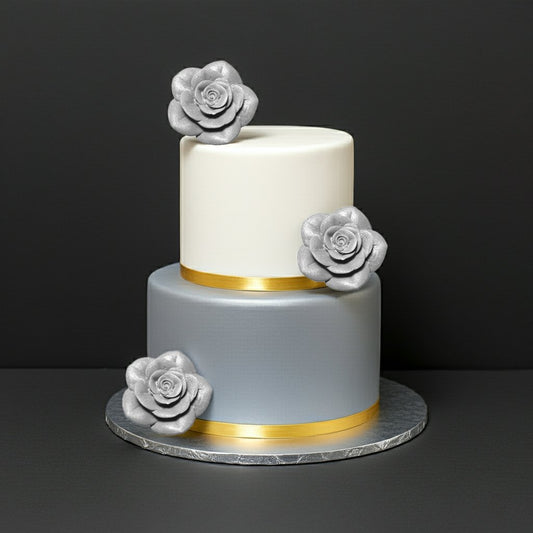 Two-tier wedding cake with silver fondant rose toppers and elegant gold ribbon accents