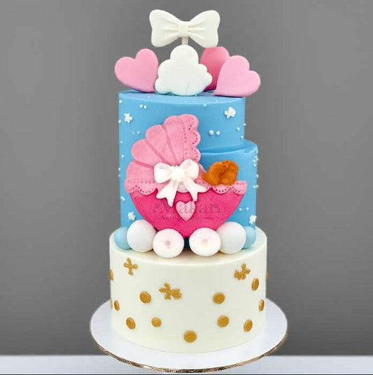 Two-tier baby shower cake decorated with a pink fondant pram, white bow, golden dots, and pink hearts on a blue tier.