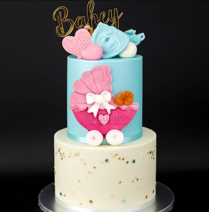Baby shower cake decorated with a pink fondant pram topper, gold “Baby” cake topper, and pastel decorations – Makai Cake Decorating Supplies