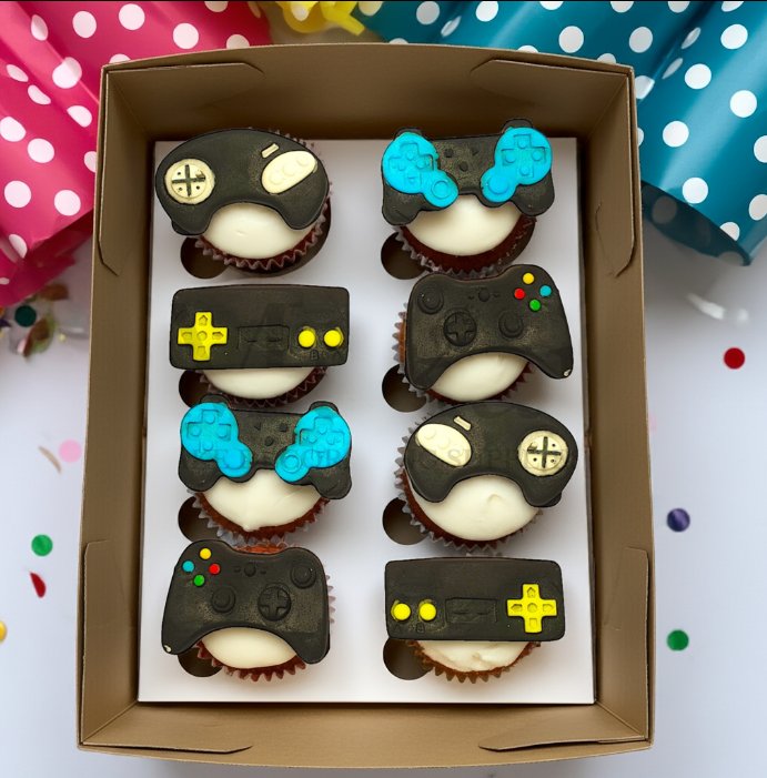 Box of cupcakes decorated with edible gaming controller toppers in different video game designs, perfect for gamers’ birthday or themed parties.