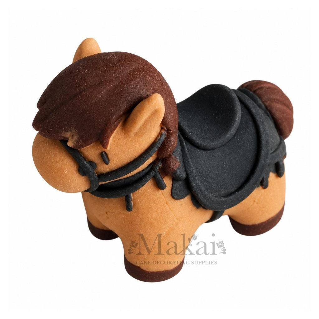 Handmade edible horse cake decoration with brown mane, black saddle and bridle, three-quarter view.