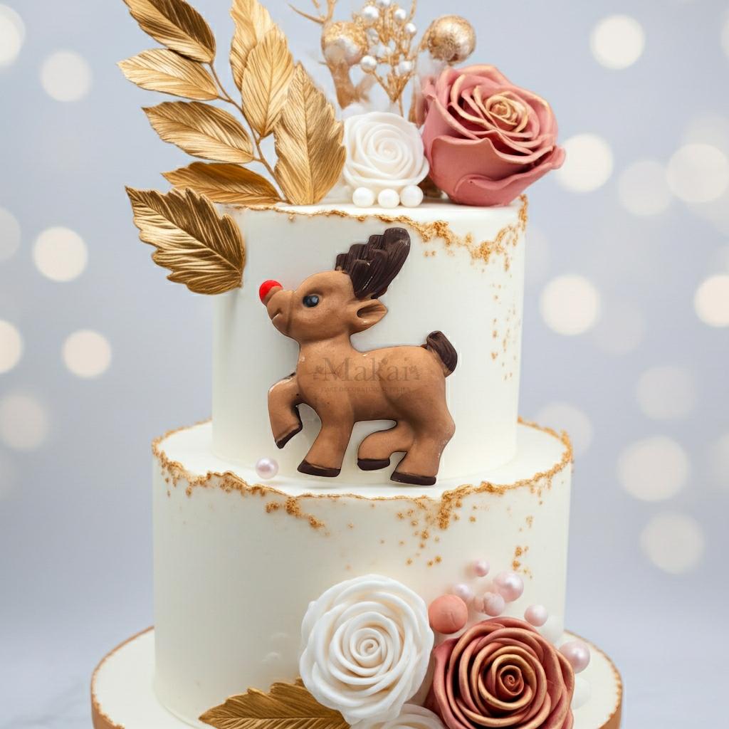 Two-tier Christmas cake decorated with gold leaves, sugar flowers and a handmade Rudolph reindeer topper