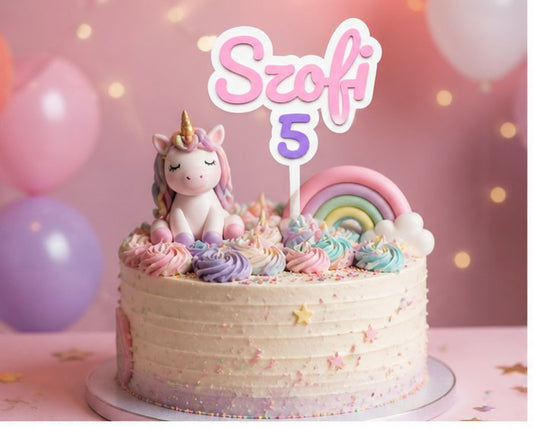 Unicorn cake with 'Szofi 5' topper against a pink background with balloons