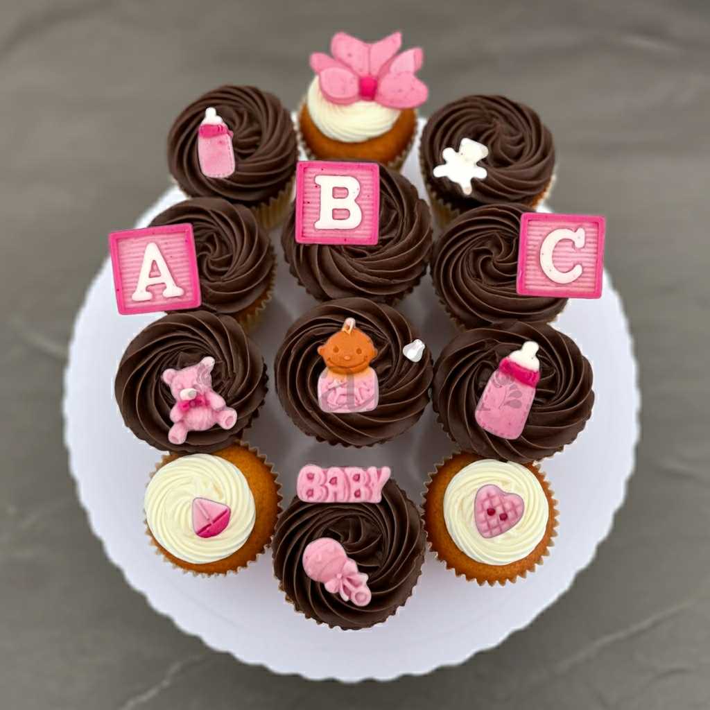 Chocolate and vanilla cupcakes decorated with edible baby girl toppers – perfect for baby shower or gender reveal