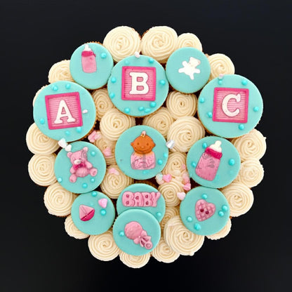 Set of baby shower cupcakes with pink ABC blocks and baby accessories toppers