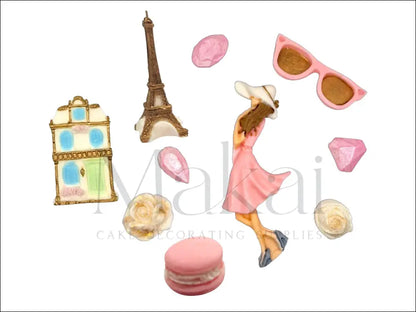Paris-themed fondant cake decoration set with Eiffel Tower, Parisian building, stylish woman, macaron, sunglasses, roses, and gems.