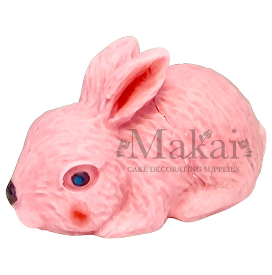 Edible pastel pink lying bunny cake topper with blue eyes for baby‑girl cakes
