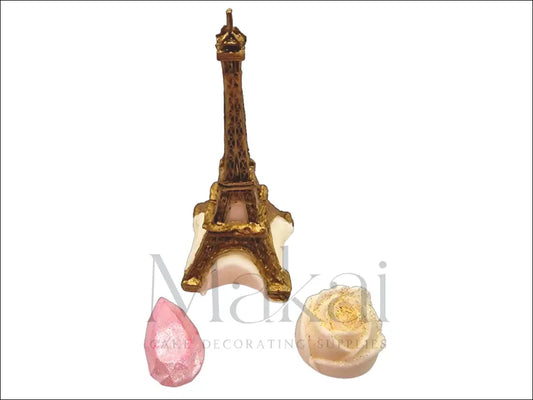 Gold Eiffel Tower, white rose with gold shimmer, and pink diamond-shaped fondant cake decorations.