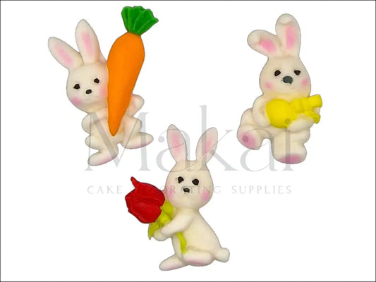 Fondant bunny trio cake decoration with carrot, flower, and another element.