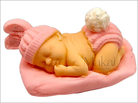 Sleeping baby cake decoration in pink, resting on a matching pink pillow with a hat and diaper.