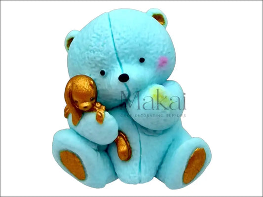 Blue edible teddy bear holding a small golden bunny, with gold details on ears, paws.