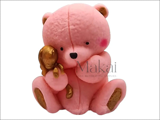 Pink edible teddy bear holding a small golden bunny, with gold details on ears, paws.