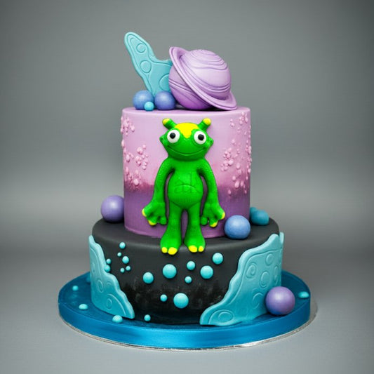 Purple galaxy theme cake with green alien topper and edible planets – Makai Cake Decorating Supplies
