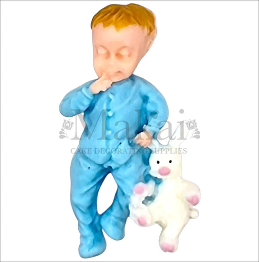Baby boy in blue pyjamas holding a white bunny cake topper.