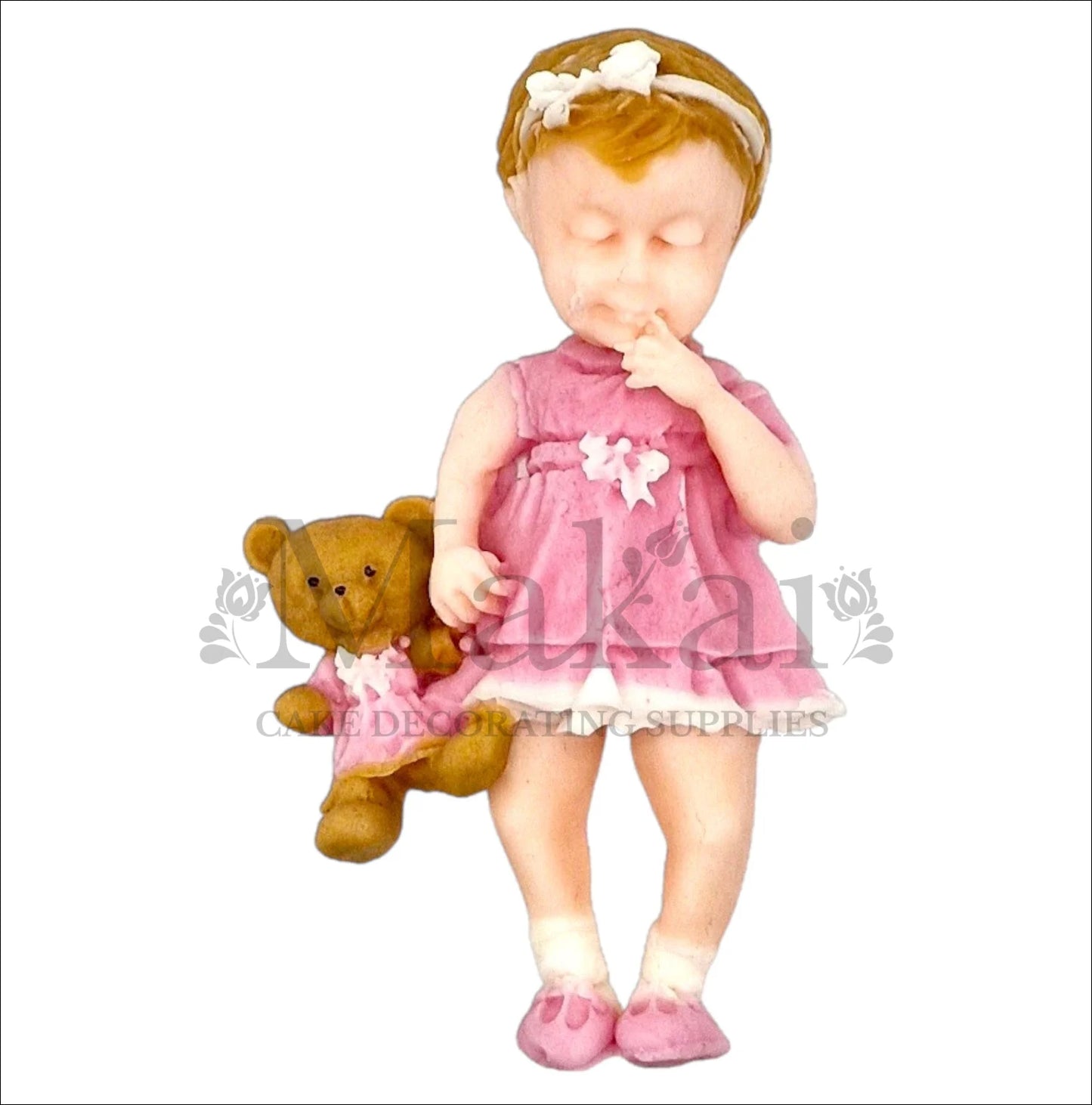 Baby girl in pink dress holding teddy bear cake topper.