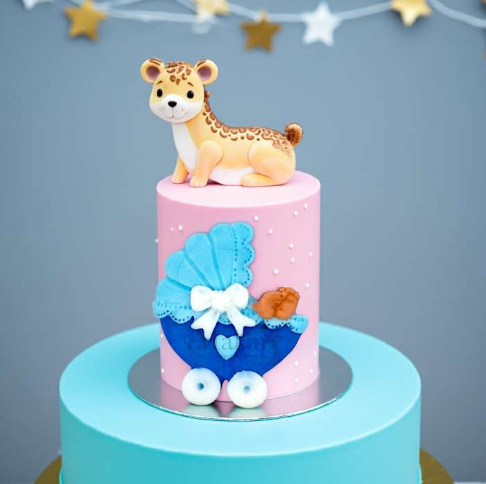 Baby shower cake with fondant giraffe topper and blue pram decoration, designed by Makai Cake Decorating Supplies.