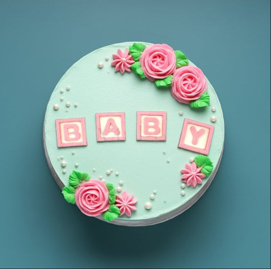 Baby shower cake decorated with pink roses, sugar pearls, and BABY letter blocks – handmade design by Makai Cake Decorating Supplies.