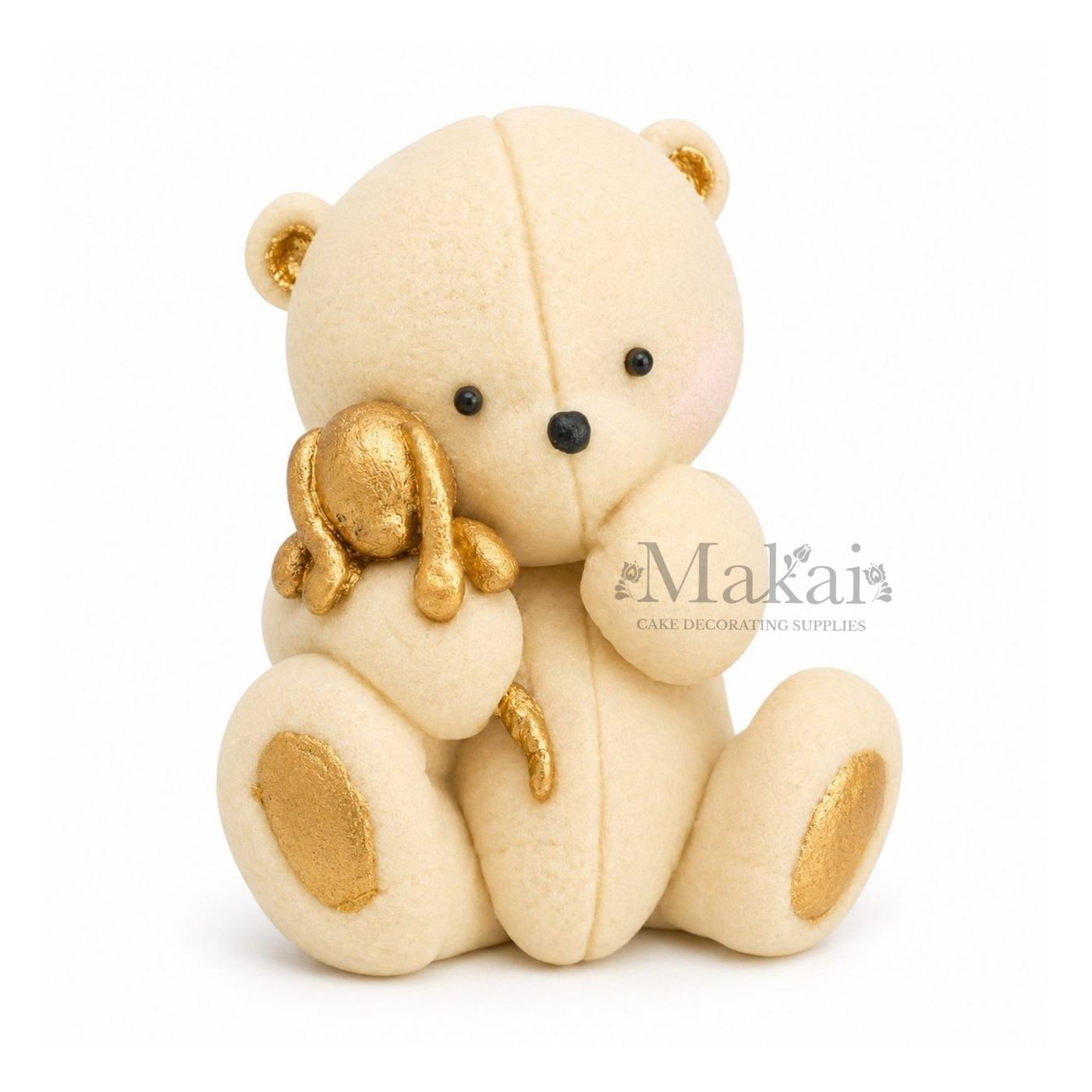Beige teddy bear fondant cake topper holding a gold bunny decoration, front view