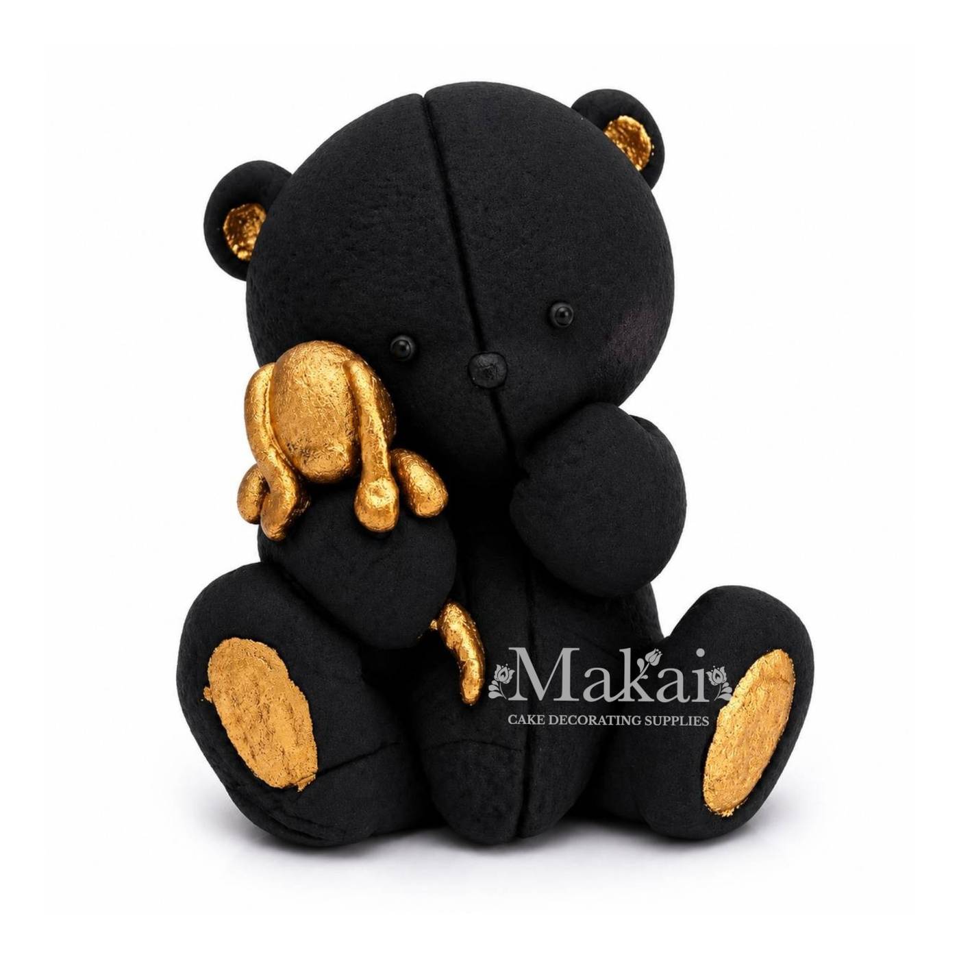 Black teddy bear fondant cake topper holding a gold bunny decoration, front view