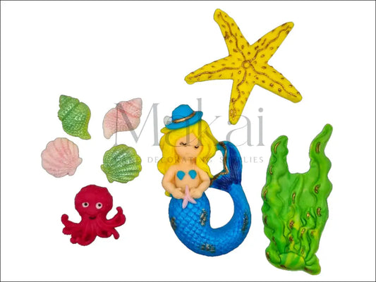 A blue mermaid cake topper set featuring a mermaid with a shimmering tail, colourful seashells, a starfish, ocean plants, and a bright red octopus for an under-the-sea-themed cake.
