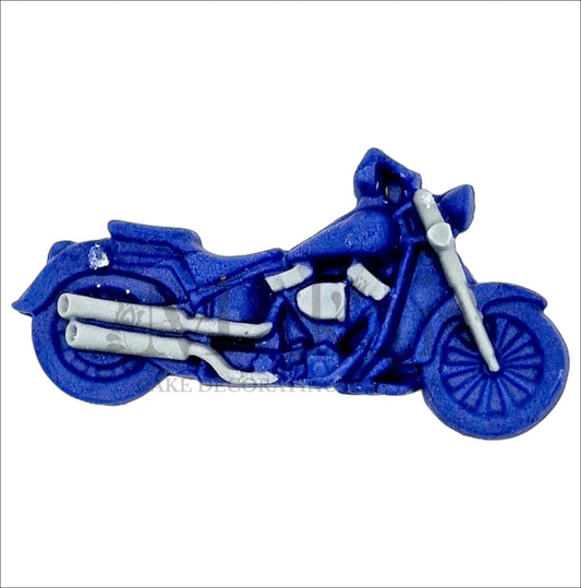 Edible blue fondant motorbike cake topper with silver pipes for biker‑themed cakes.