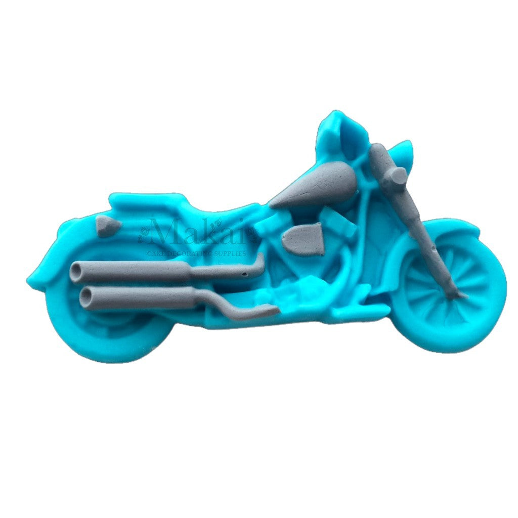 Edible blue fondant motorbike cake topper with silver pipes for biker‑themed cakes.