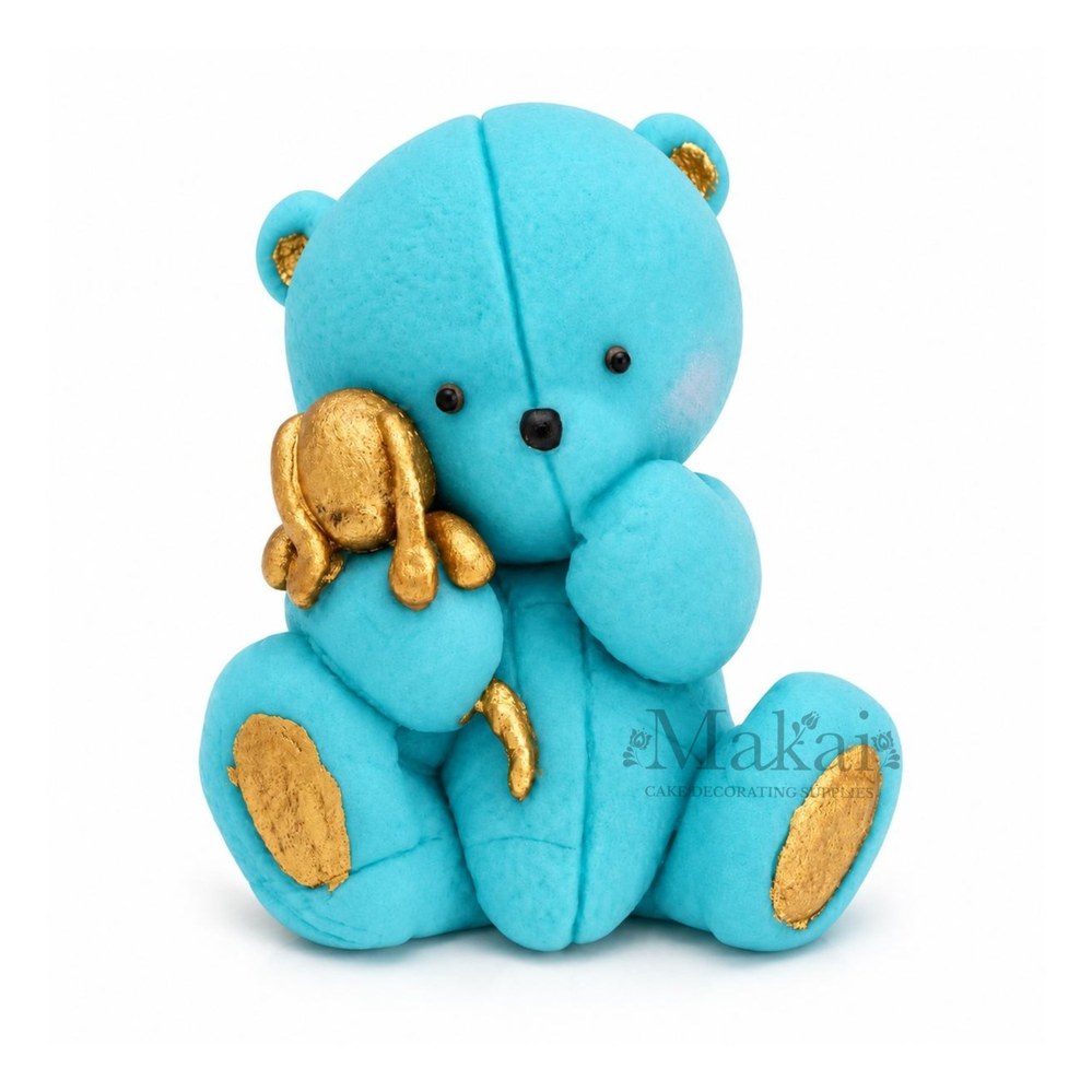 Blue teddy bear fondant cake topper holding a gold bunny decoration, front view