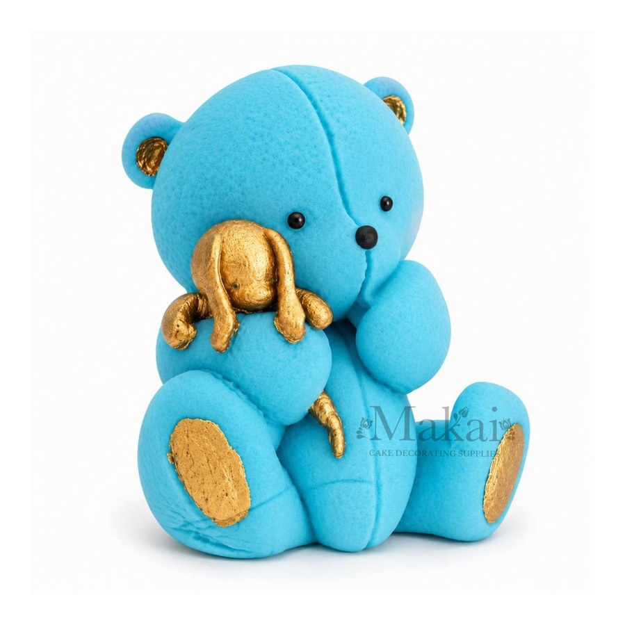 Blue teddy bear fondant cake topper holding a gold bunny decoration, side view
