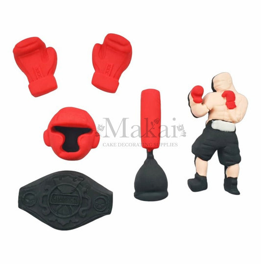 Set of boxing-themed cake decorations including red gloves, headgear, a punching bag, and a boxer figure on a white background.