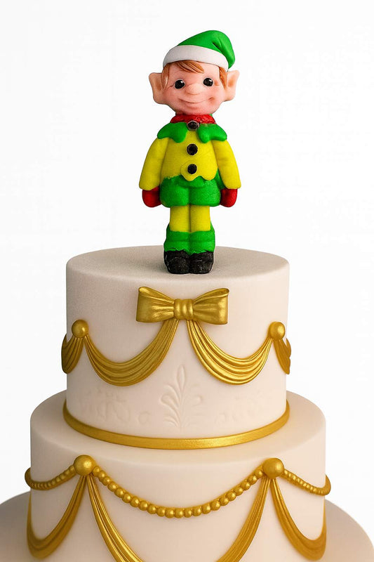 Two-tier white Christmas cake decorated with gold fondant details and a handmade elf cake topper on top
