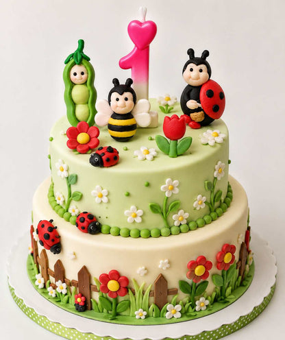 Two-tier garden themed first birthday cake decorated with handmade fondant ladybugs, bee, flowers, pea pod character and pink number 1 candle