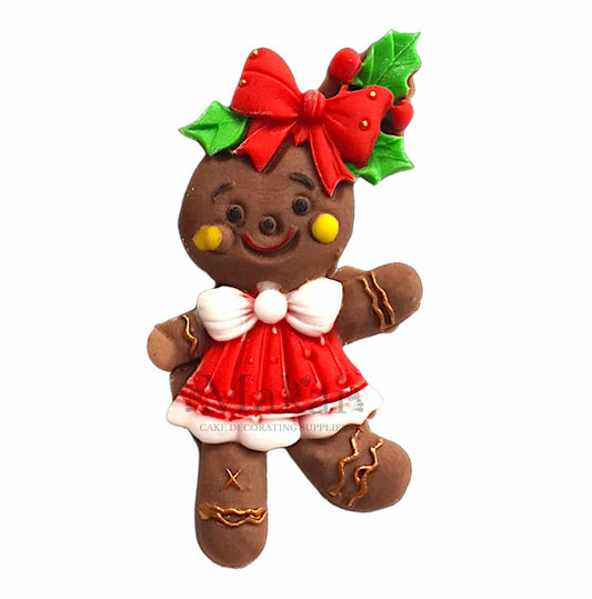 Edible gingerbread girl cake topper wearing a red dress with a holly bow and festive details.