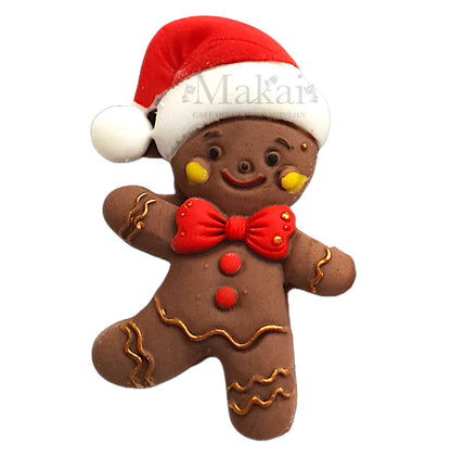 Handcrafted gingerbread man cake topper wearing a Santa hat with red bow and gold icing details.