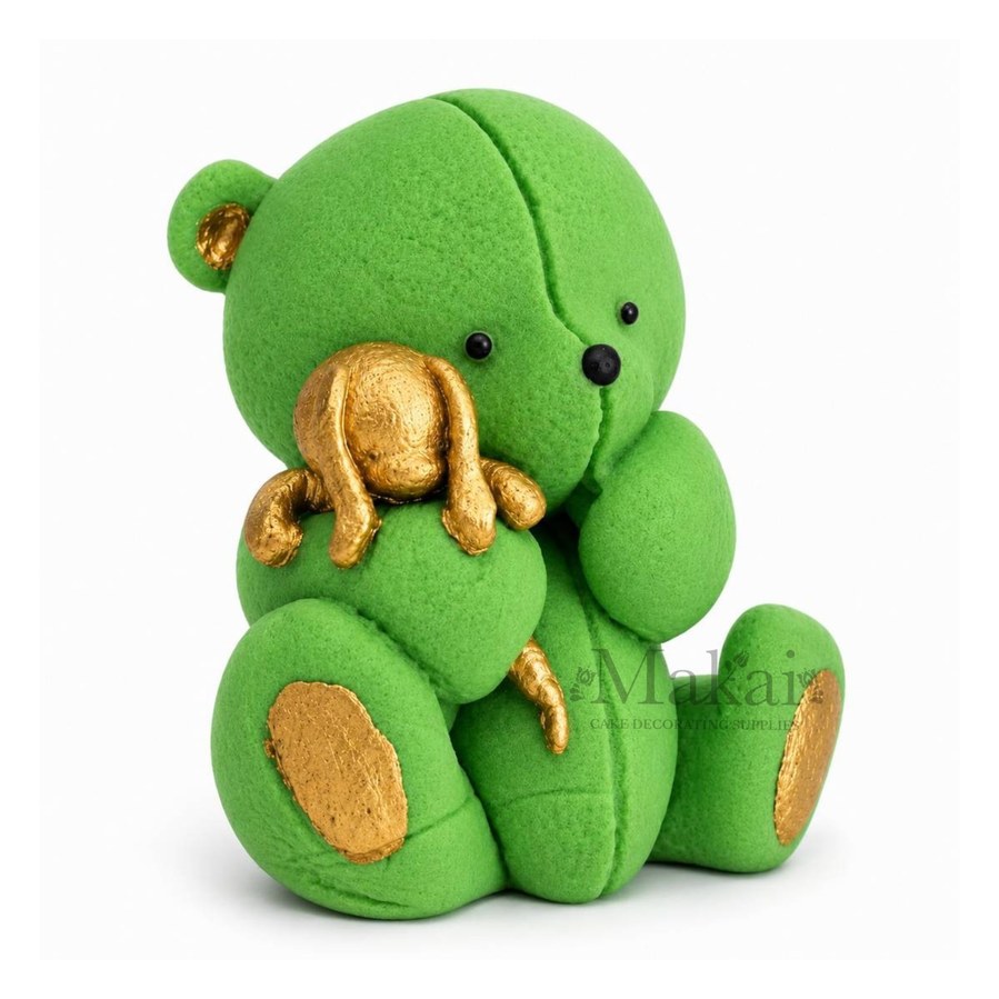 Green teddy bear fondant cake topper holding a gold bunny decoration, side view