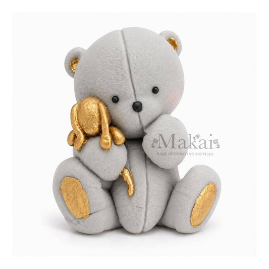 Grey teddy bear fondant cake topper holding a gold bunny decoration, front view