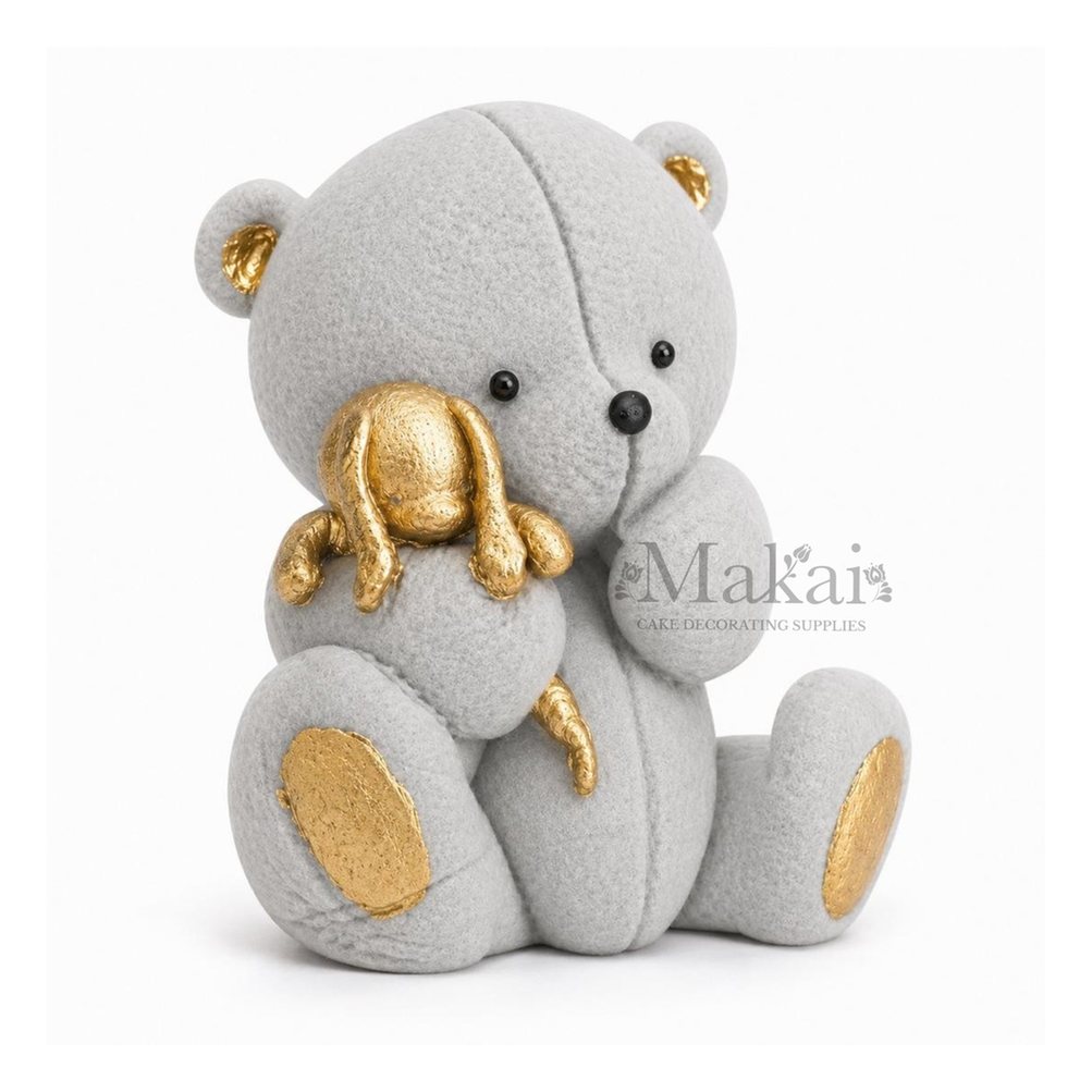Grey teddy bear fondant cake topper holding a gold bunny decoration, side view
