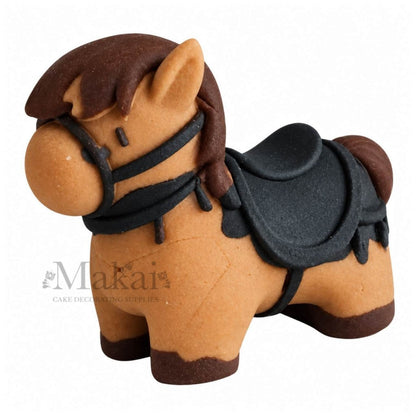 Edible handmade fondant horse cake topper with brown mane, black saddle and detailed bridle on white background.
