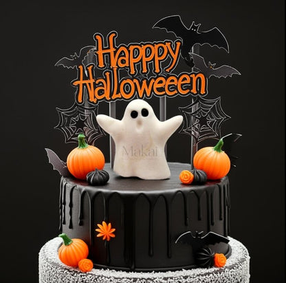 Black Halloween cake with a fondant ghost topper, pumpkins, bats, and spiderweb decorations, featuring a "Happy Halloween" sign.