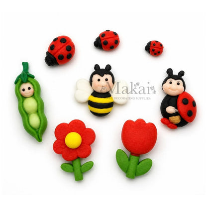 Handmade fondant garden cake decorations with ladybirds, bee, flowers and pea pod. 