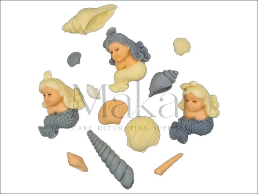 A sophisticated mini mermaid cake topper set featuring three small mermaids in grey and cream tones, accompanied by various beautifully detailed seashells, ideal for an elegant ocean-themed cake.