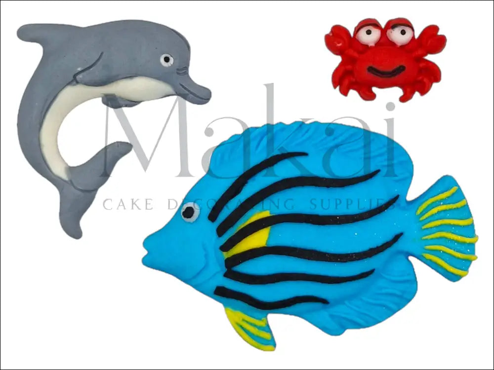 A fun ocean-themed cake topper set featuring a blue fish with black stripes, a grey dolphin, and a red crab, perfect for sea-inspired cake designs.