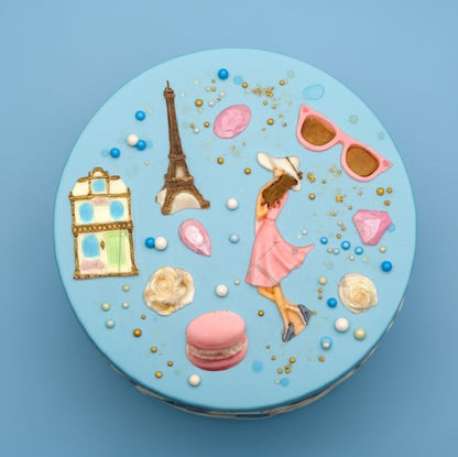 Paris themed edible cake decorations with Eiffel Tower, fashion girl, macarons and roses on a blue cake topper
