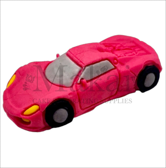 Edible hot‑pink fondant sports car cake topper with black wheels and yellow headlights.