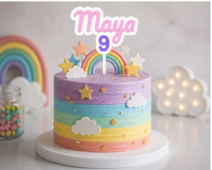 Colorful birthday cake with rainbow and cloud decorations, featuring the name 'Maya' and age '9'.