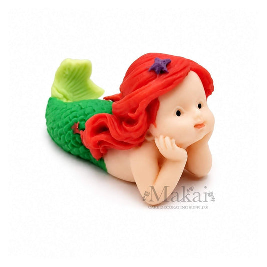 Lying mermaid baby edible cake topper with green tail and red hair, ideal for ocean and fantasy-themed cakes.
