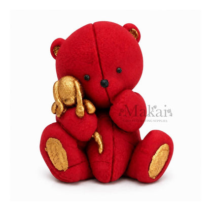 Red teddy bear fondant cake topper holding a gold bunny decoration, front view