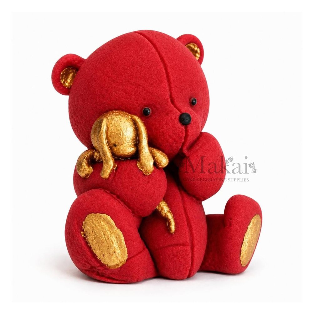 Red teddy bear fondant cake topper holding a gold bunny decoration, side view