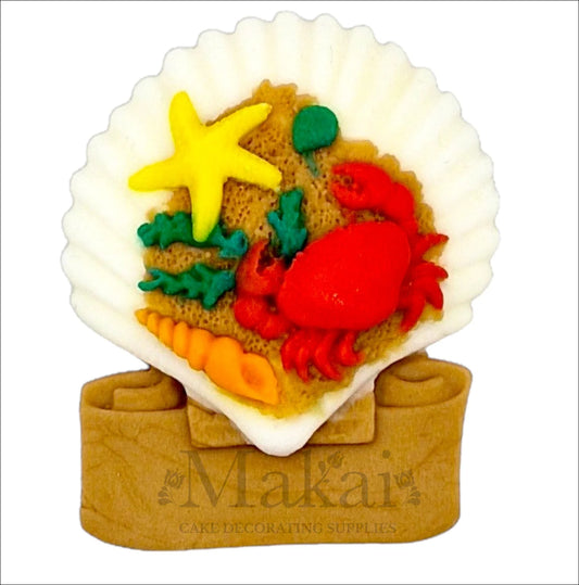Ocean-themed cake topper featuring a white shell filled with a red crab, yellow starfish and colourful coral.